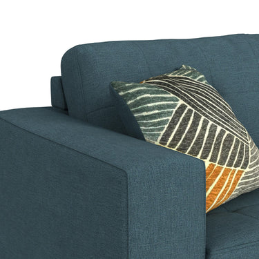 Close-up of the teal chair arm and tufted back with a patterned accent pillow